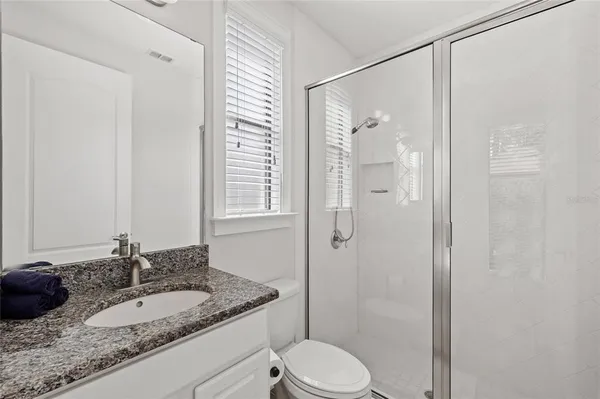 a bathroom with a granite countertop sink toilet and shower