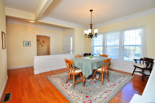 a dining room with wooden floor a chandelier a wooden table and chairs