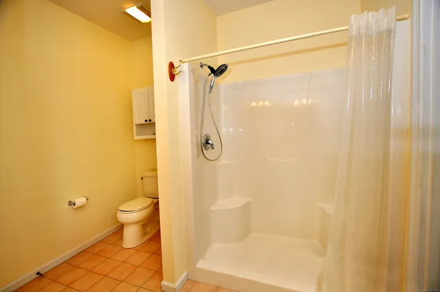 a bathroom with a granite countertop shower and a toilet