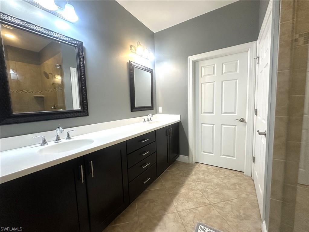 13462 Kent Street Naples, FL 34109 - Photo 16 of 30 a spacious bathroom with a double vanity sink and a mirror