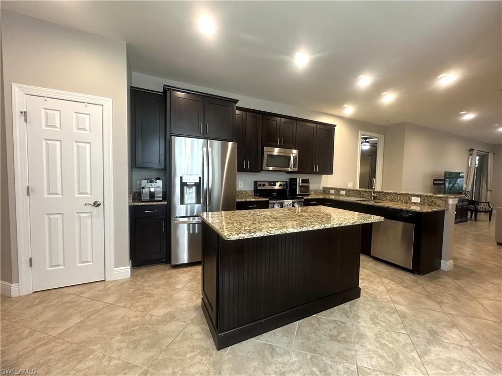 13462 Kent Street Naples, FL 34109 - Photo 3 of 30 a kitchen with kitchen island stainless steel appliances a sink stove and refrigerator
