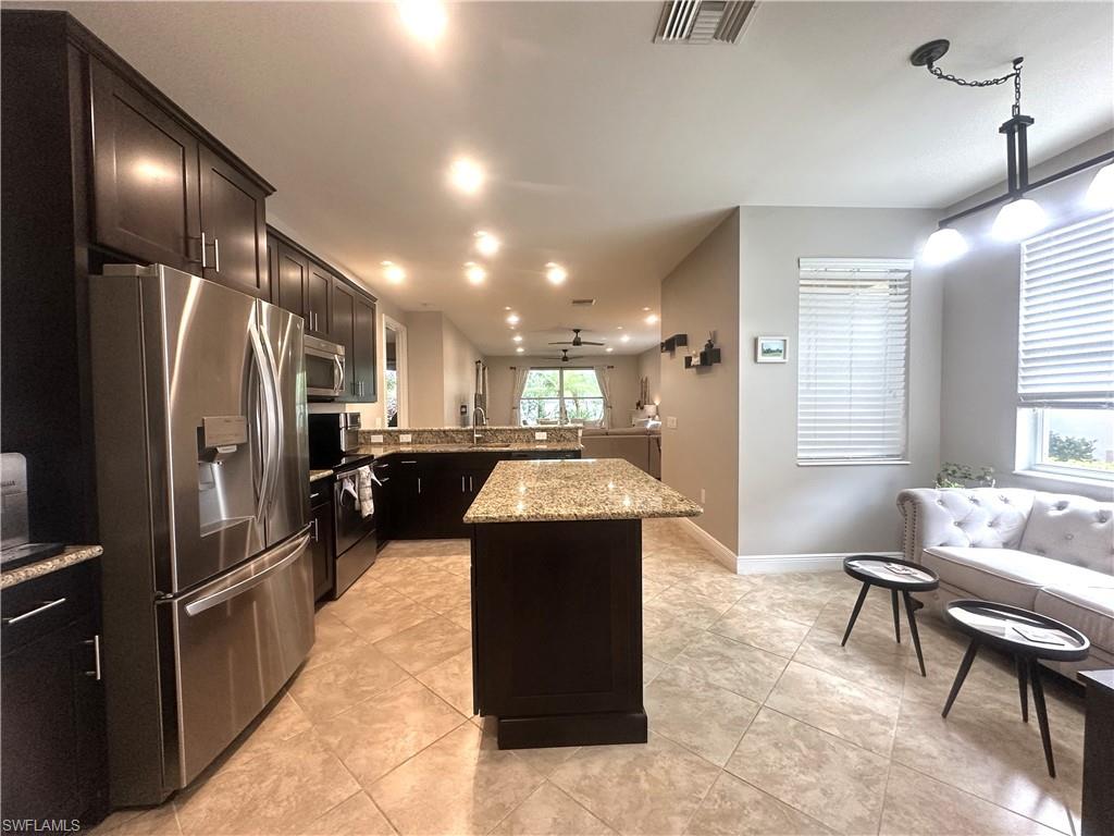 13462 Kent Street Naples, FL 34109 - Photo 5 of 30 a kitchen with kitchen island a counter top space a sink stainless steel appliances and a window