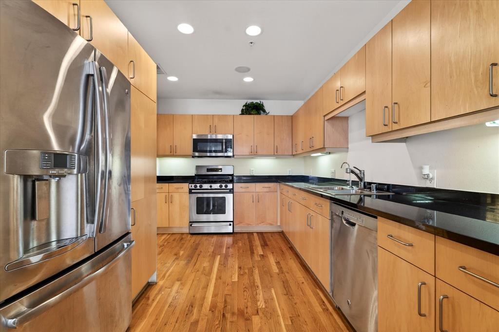 a kitchen with kitchen island granite countertop a sink a counter top space stainless steel appliances and cabinets