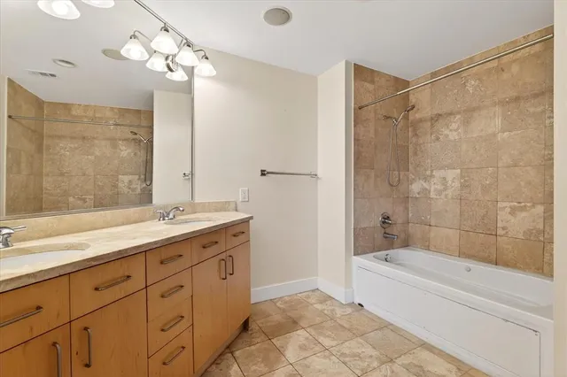 a bathroom with a granite countertop sink a large mirror and a bathtub