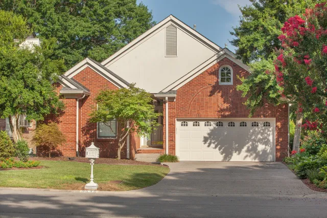 a view of a white house next to a yard with big trees