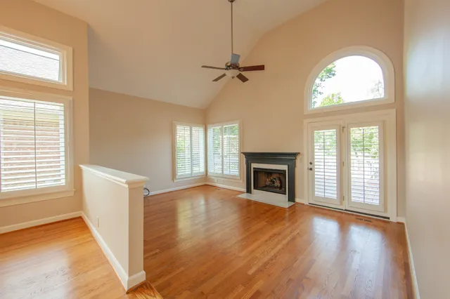 an empty room with windows a fireplace a kitchen and windows