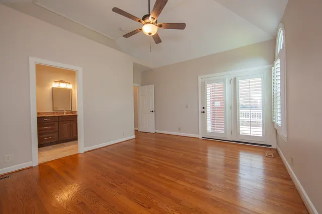 a view of an empty room with a window and wooden floor