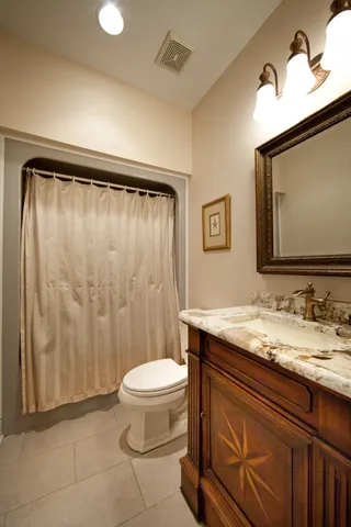 a bathroom with a granite countertop sink toilet and mirror