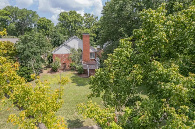 a aerial view of a house with a yard and large trees