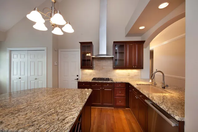 a kitchen with kitchen island granite countertop a sink stainless steel appliances cabinets and a counter top space