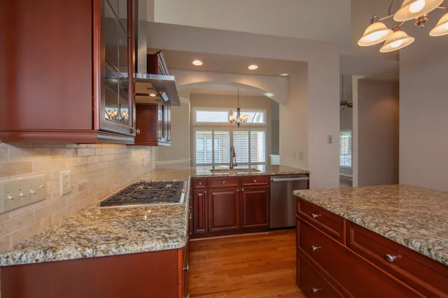 a kitchen with stainless steel appliances granite countertop wooden cabinets and a stove top oven