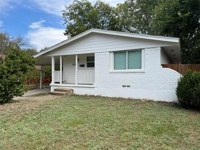 a white house that has a small yard and a large tree