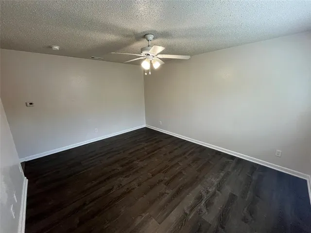 an empty room with wooden floor fan and window