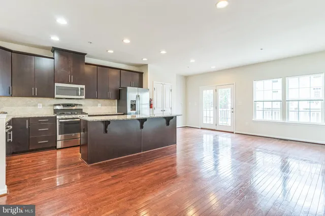 a large kitchen with stainless steel appliances granite countertop a large counter top a stove and a wooden floors
