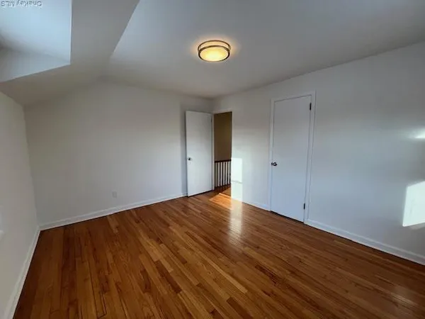 a view of an empty room with wooden floor and window