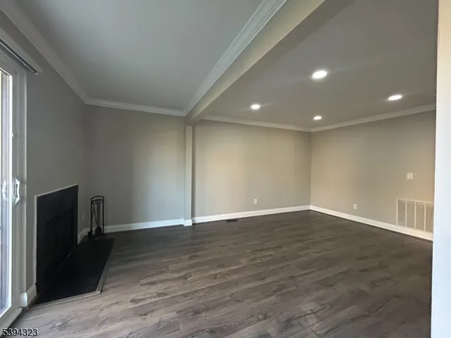 a view of an empty room with wooden floor and a fireplace