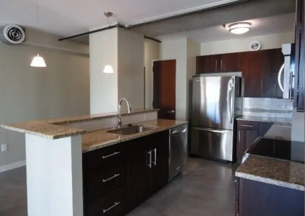 a kitchen with stainless steel appliances granite countertop a refrigerator a sink and a stove