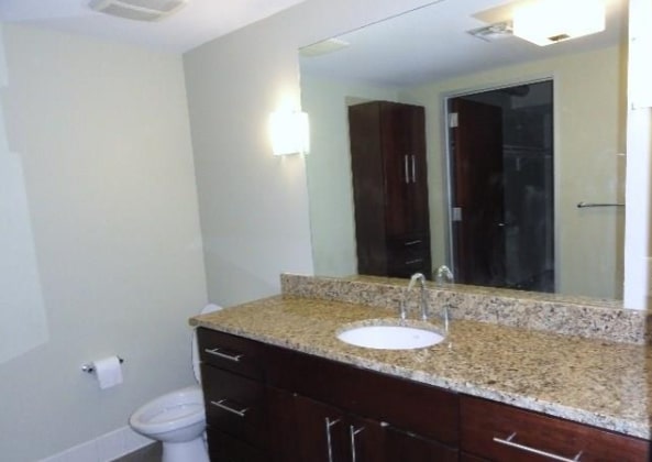 800 Brazos Street, Unit 1006 Austin, TX 78701 - Photo 10 of 26 a bathroom with a granite countertop sink a toilet and a mirror