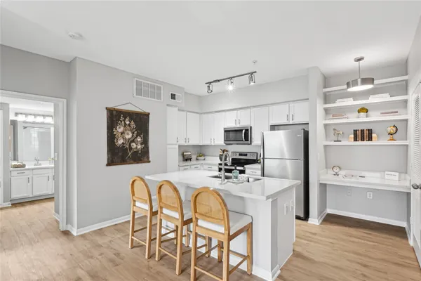 a kitchen with stainless steel appliances a refrigerator a stove a sink dishwasher and white cabinets with wooden floor