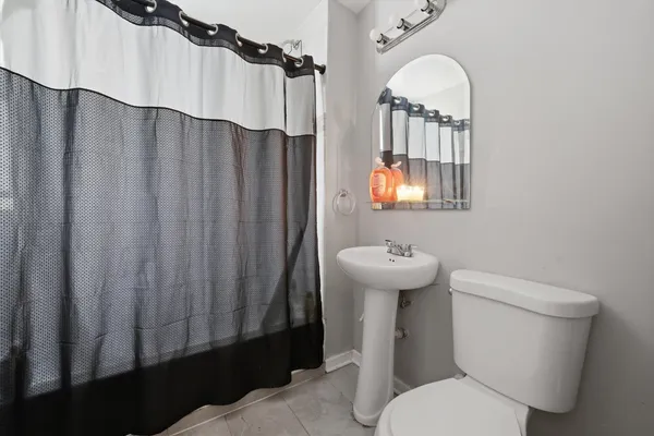 a bathroom with a sink a mirror a toilet and a window