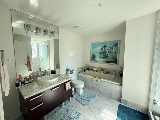 a bathroom with a double vanity sink toilet mirror and tub