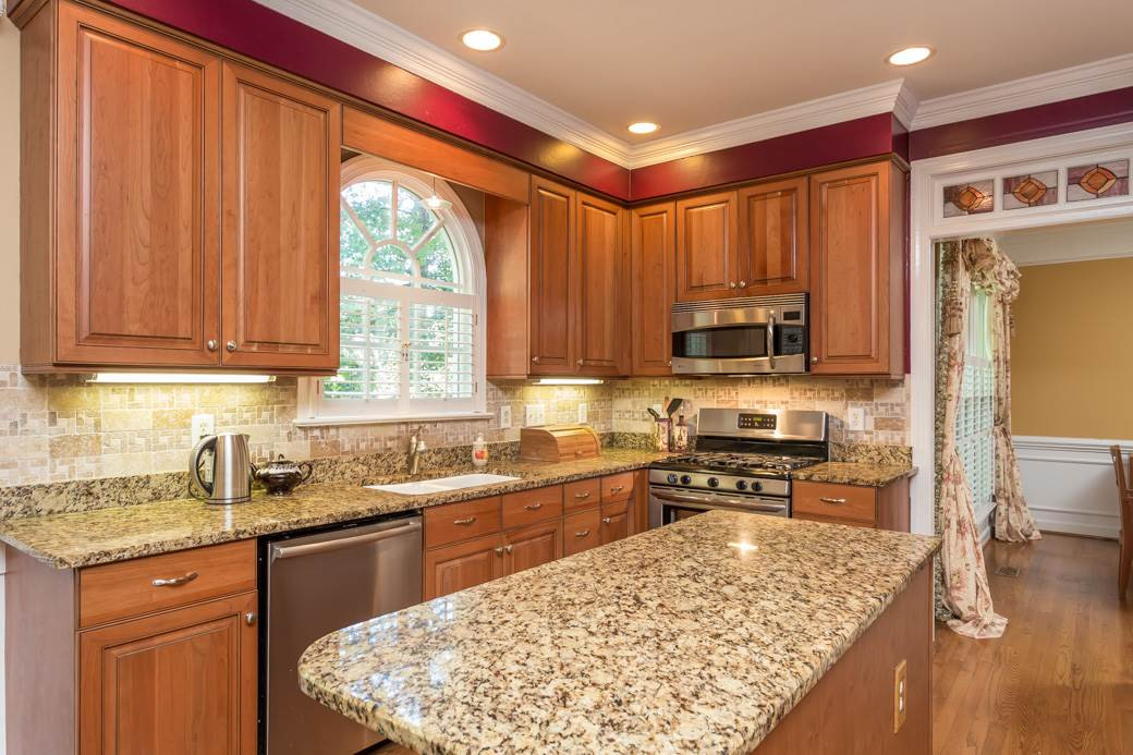 5215 Coffee Tree Drive Raleigh, NC 27613 - Photo 4 of 25 The remodeled kitchen features gorgeous granite countertops, cherry soft-close cabinets and stone-tile backsplash Kitchen