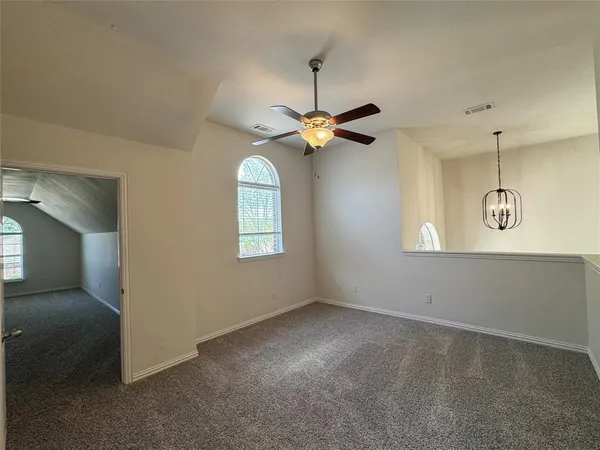 an empty room with windows and ceiling fan