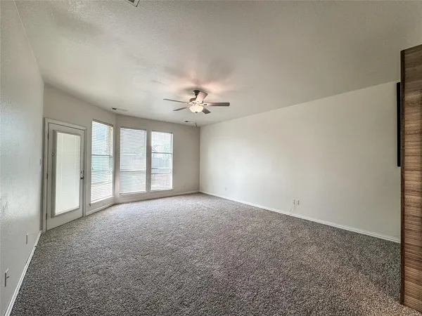 an empty room with a window and a fan