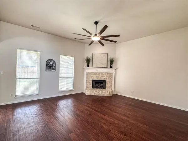 a view of a livingroom with a fireplace a ceiling fan and wooden floor