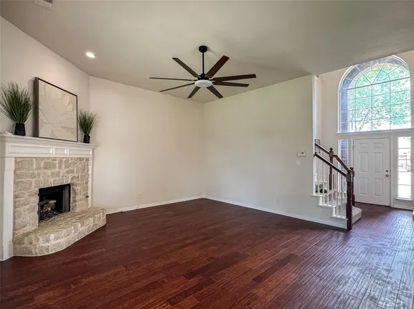 a view of a livingroom with a fireplace a ceiling fan and wooden floor
