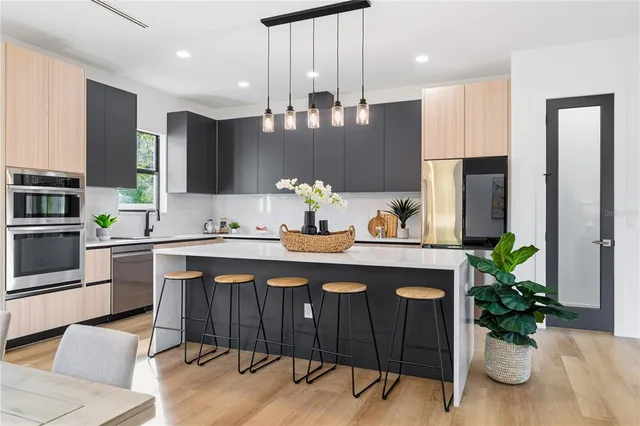 a kitchen with stainless steel appliances kitchen island granite countertop a refrigerator a stove a sink dishwasher with a dining table and chairs