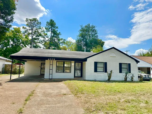 a front view of house with yard and trees in the background