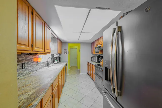 a kitchen with stainless steel appliances granite countertop a refrigerator a stove and a sink with wooden floor
