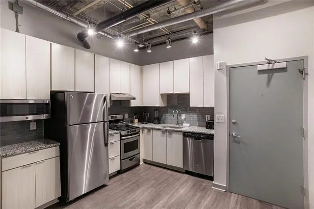 a kitchen with stainless steel appliances granite countertop a refrigerator a stove a sink and a microwave