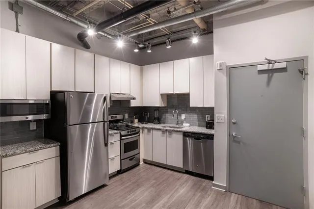 a kitchen with granite countertop stainless steel appliances a refrigerator a sink and cabinets