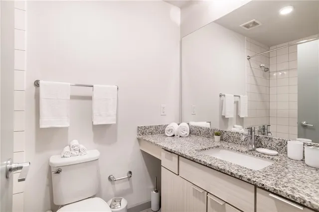 a bathroom with a granite countertop sink a mirror and a toilet