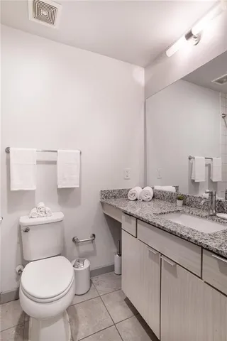 a bathroom with a granite countertop toilet sink and mirror