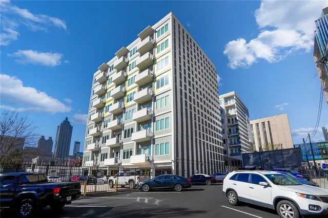 a front view of a building with lot of cars and trees