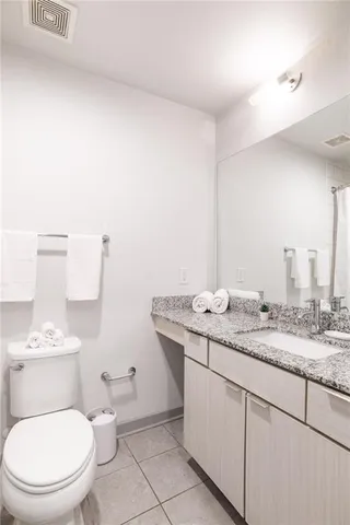 a bathroom with a granite countertop toilet sink and mirror