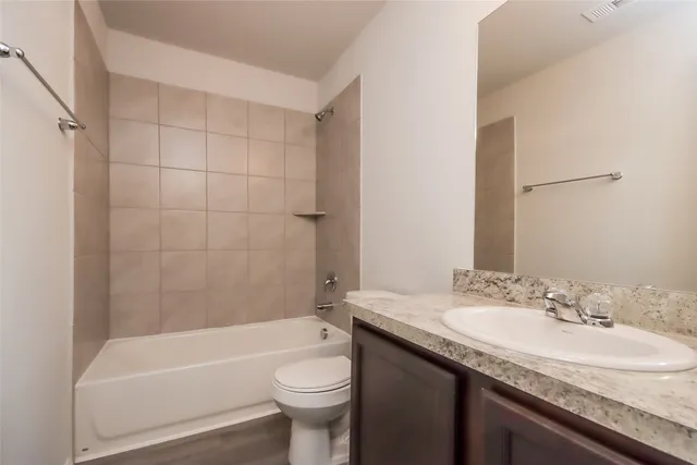 a bathroom with a granite countertop sink a toilet and bathtub