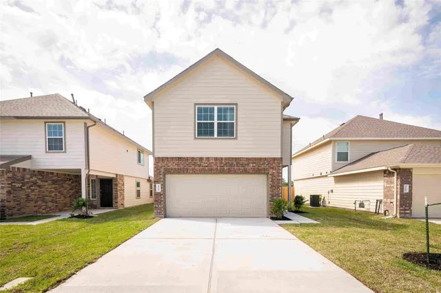 a view of a white house next to a yard with a big yard and large tree