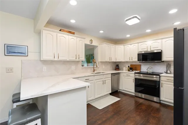 a kitchen with granite countertop a sink stainless steel appliances and cabinets