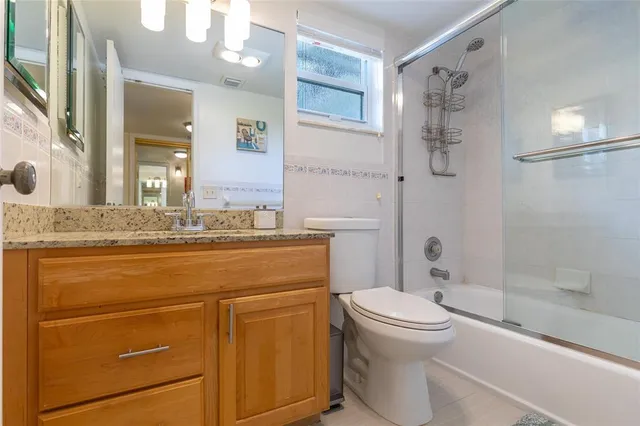 a bathroom with a granite countertop sink toilet mirror and a bathtub