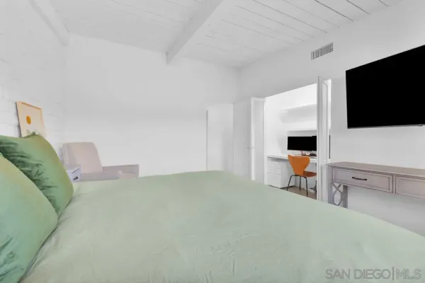 a spacious bedroom with a bed a couch and a flat screen tv