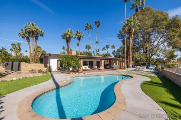 a view of swimming pool with seating area and trees in the background