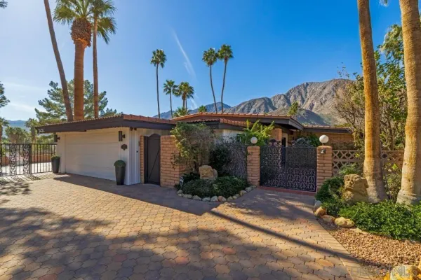 a view of a house with potted plants and palm trees