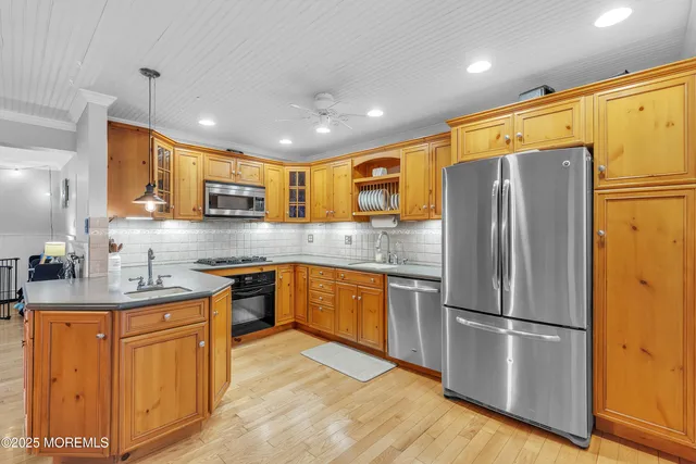 a kitchen with stainless steel appliances granite countertop a refrigerator a stove a sink a oven with wooden floor and cabinets