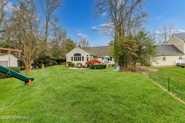 a view of white house with a big yard and large trees