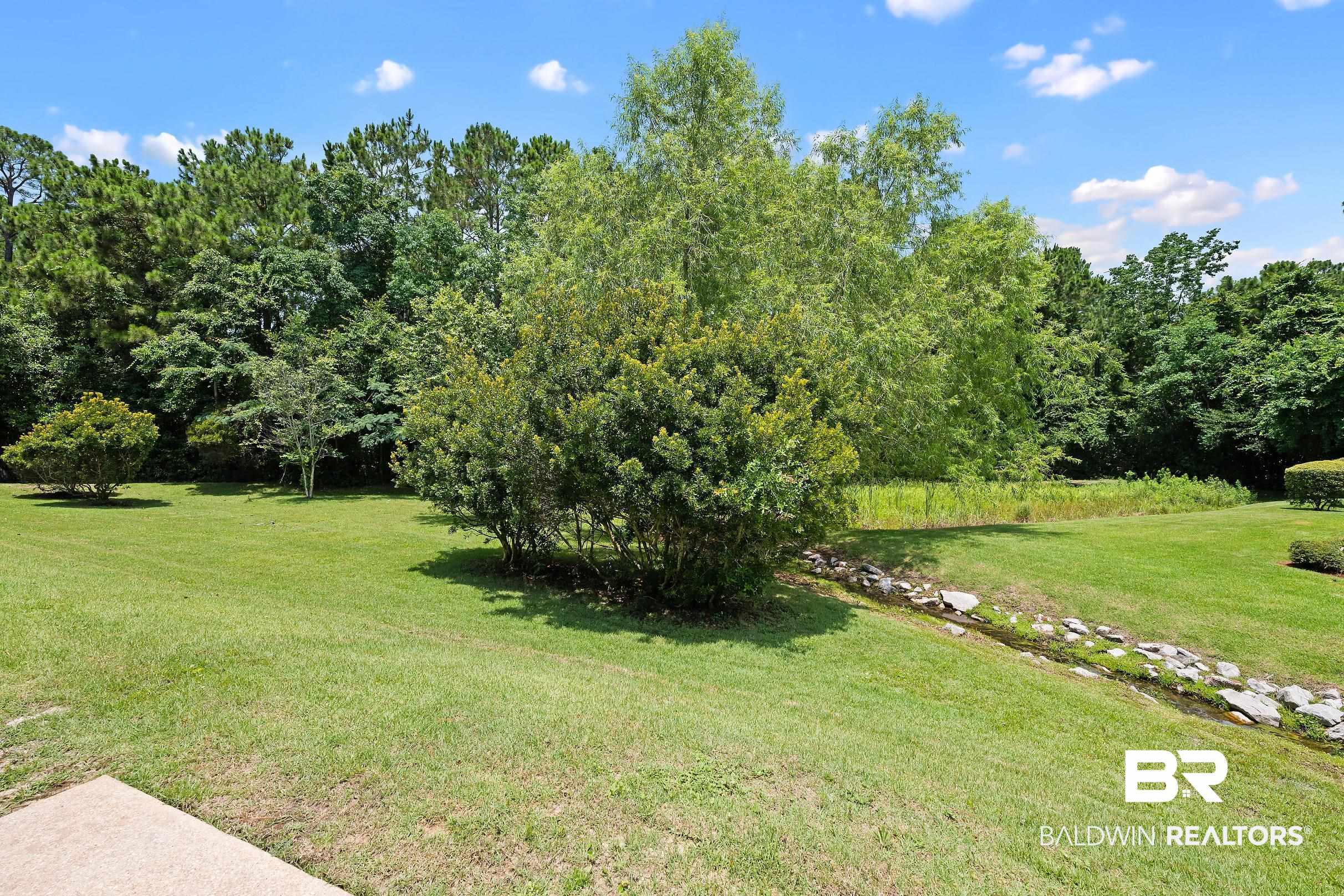 430 West Fort Morgan Road, Unit 704 Gulf Shores, AL 36542 - Photo 27 of 35 Expansive green lawn bordered by diverse mature trees and natural landscaping