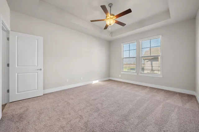 an empty room with windows and ceiling fan